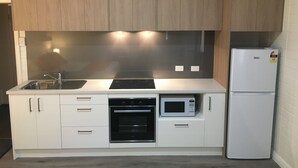 Una cocina moderna con gabinetes blancos, un lavamanos de acero inoxidable, un horno empotrado, un microondas y un refrigerador.