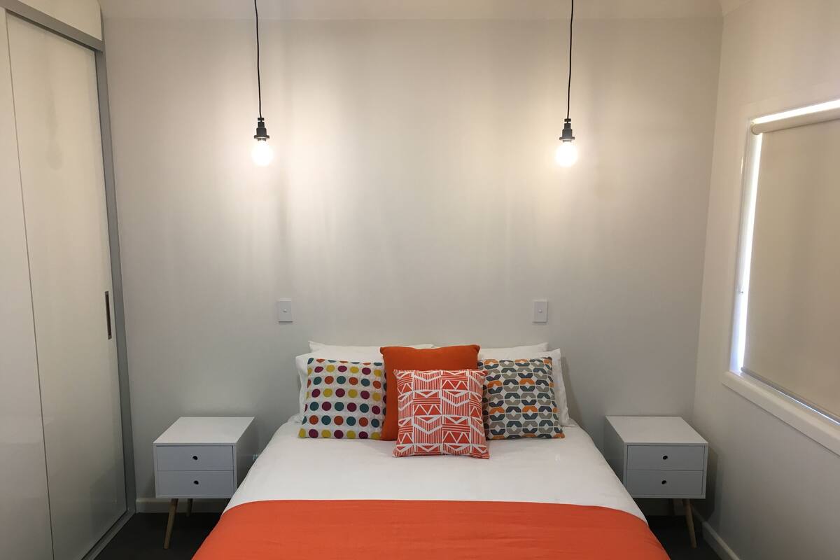 A neatly arranged bedroom with a bed, two bedside tables, and a window.