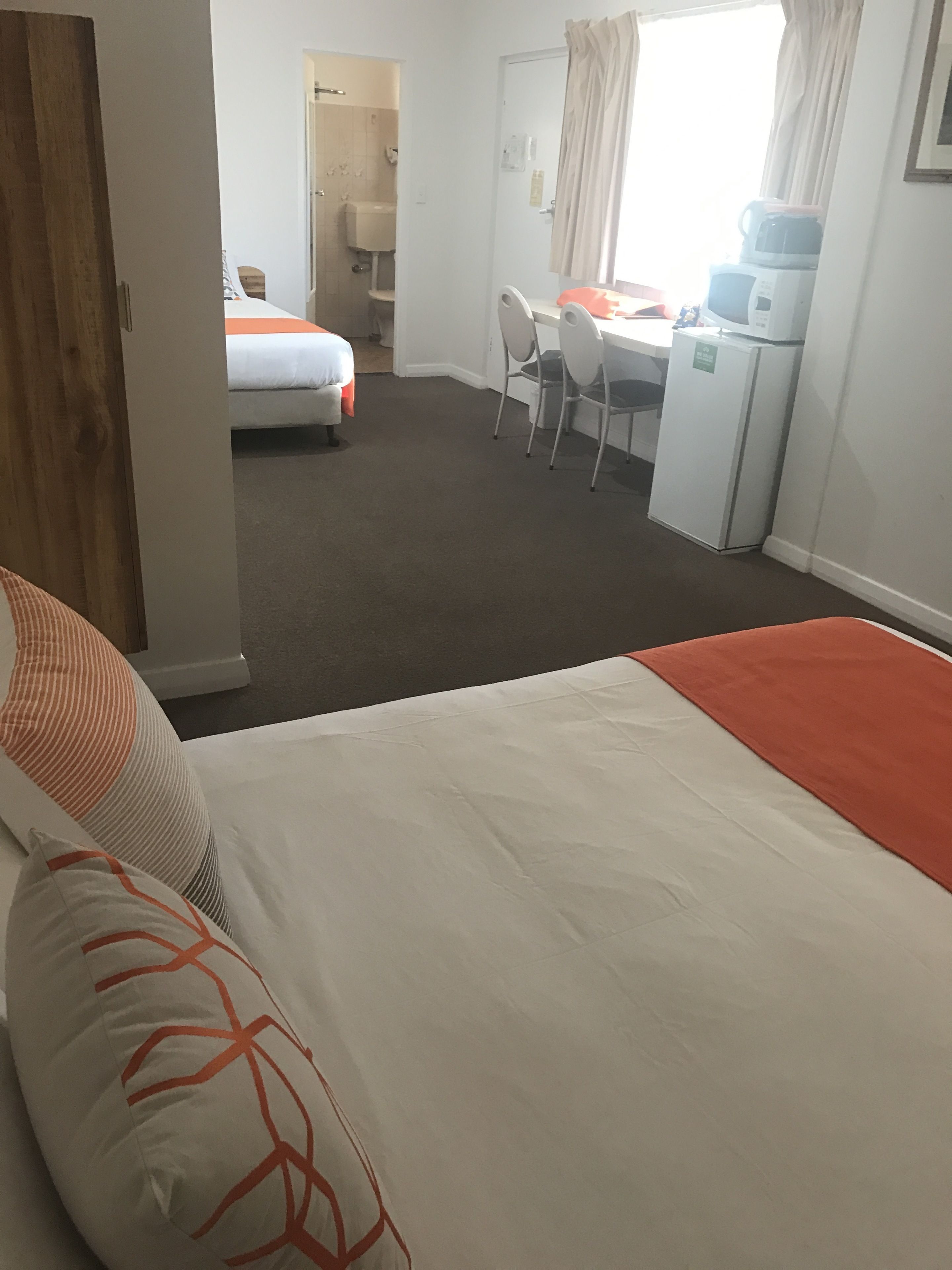 Ein Hotelzimmer mit Bett, Schreibtisch, Stuhl und einer Küchenzeile.