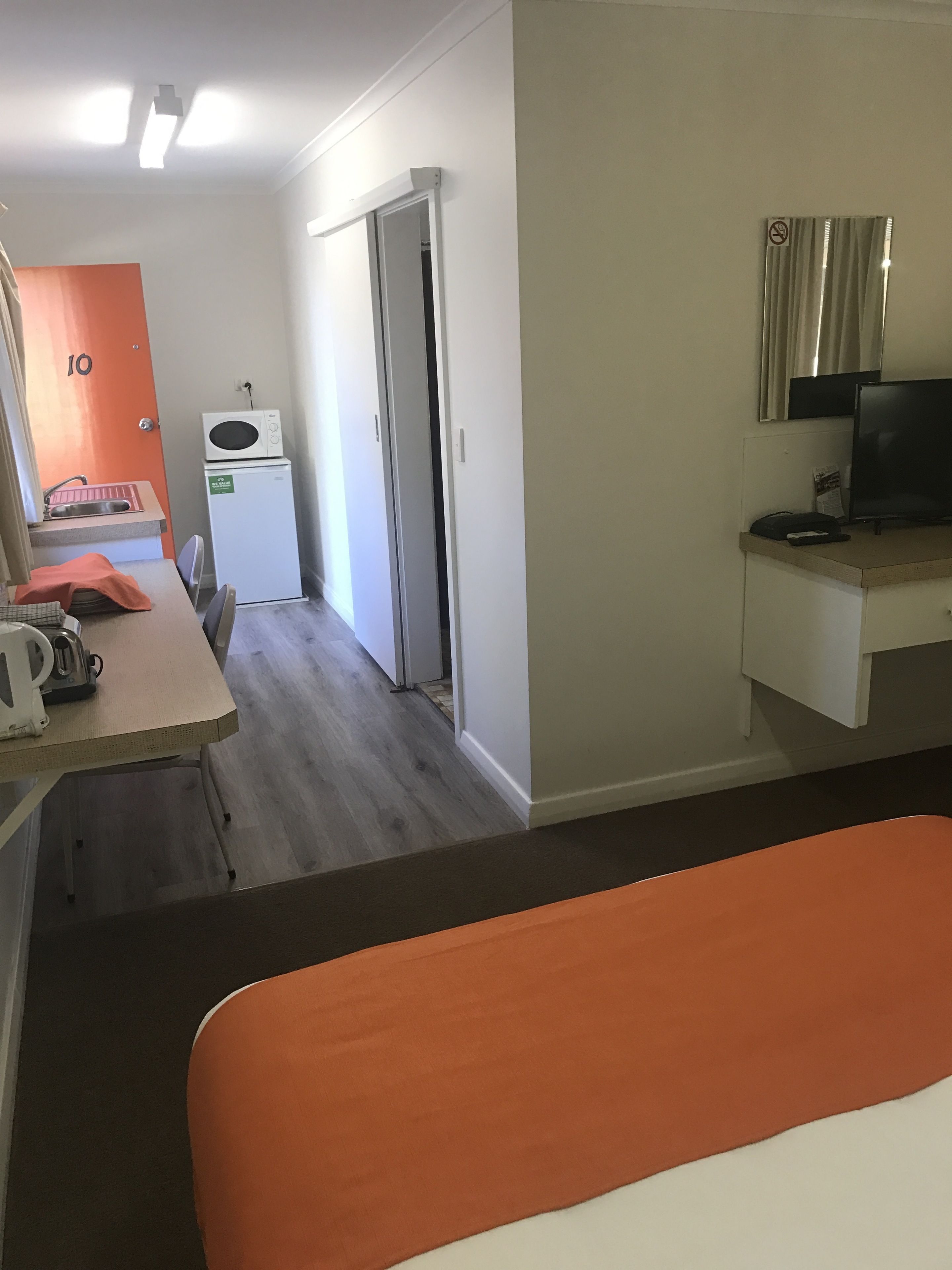 Ein Hotelzimmer mit einem Bett, einem Schreibtisch mit Computer, einer Mikrowelle, einem Kühlschrank und einer Badezimmertür.