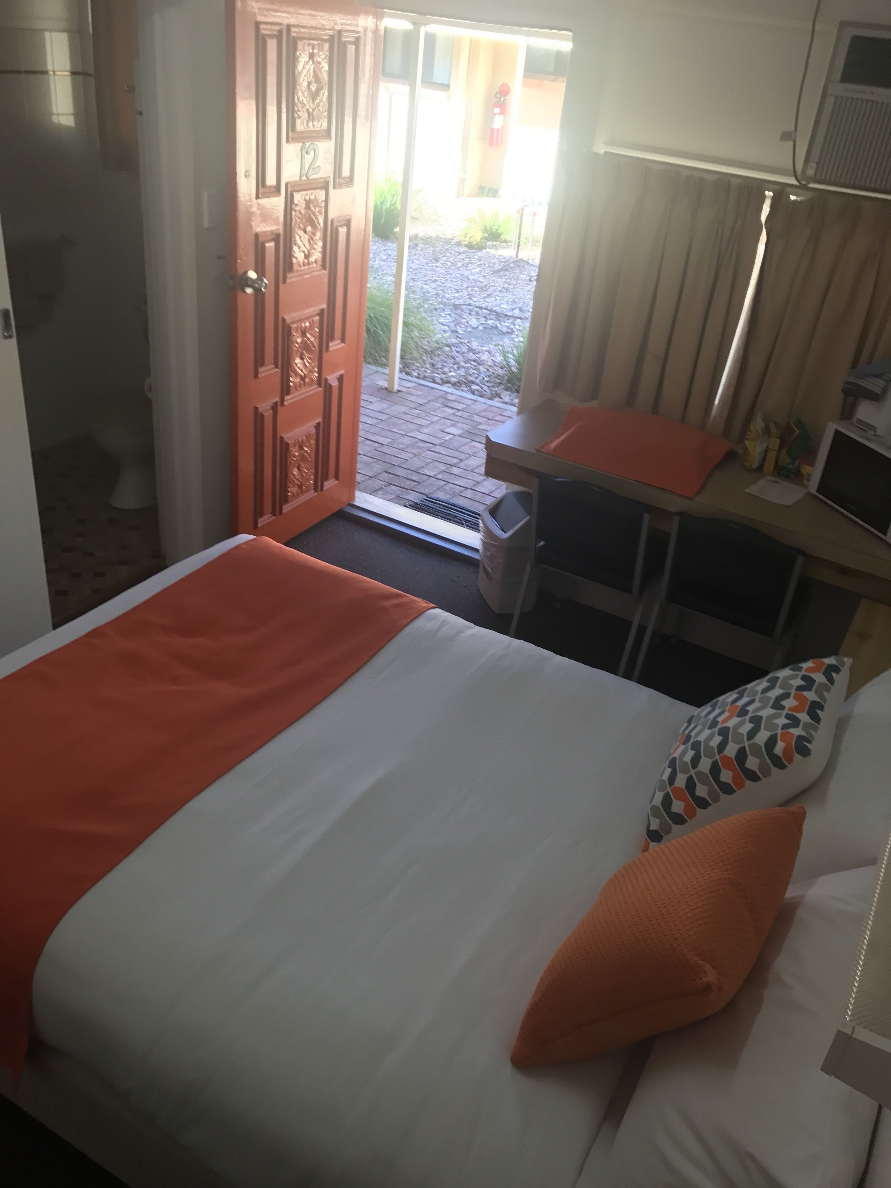 A hotel room with a bed, a desk, and a view of the outside.