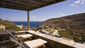 A terrace with lounge chairs overlooking a coastal landscape.