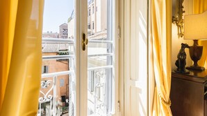 Ein Balkon mit weißer Brüstung, Blick auf Gebäude, und eine Tür mit goldener Klinke.