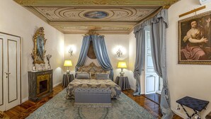 Ein luxuriöses Schlafzimmer mit einem großen Bett, einer verzierten Decke und klassischer Einrichtung.