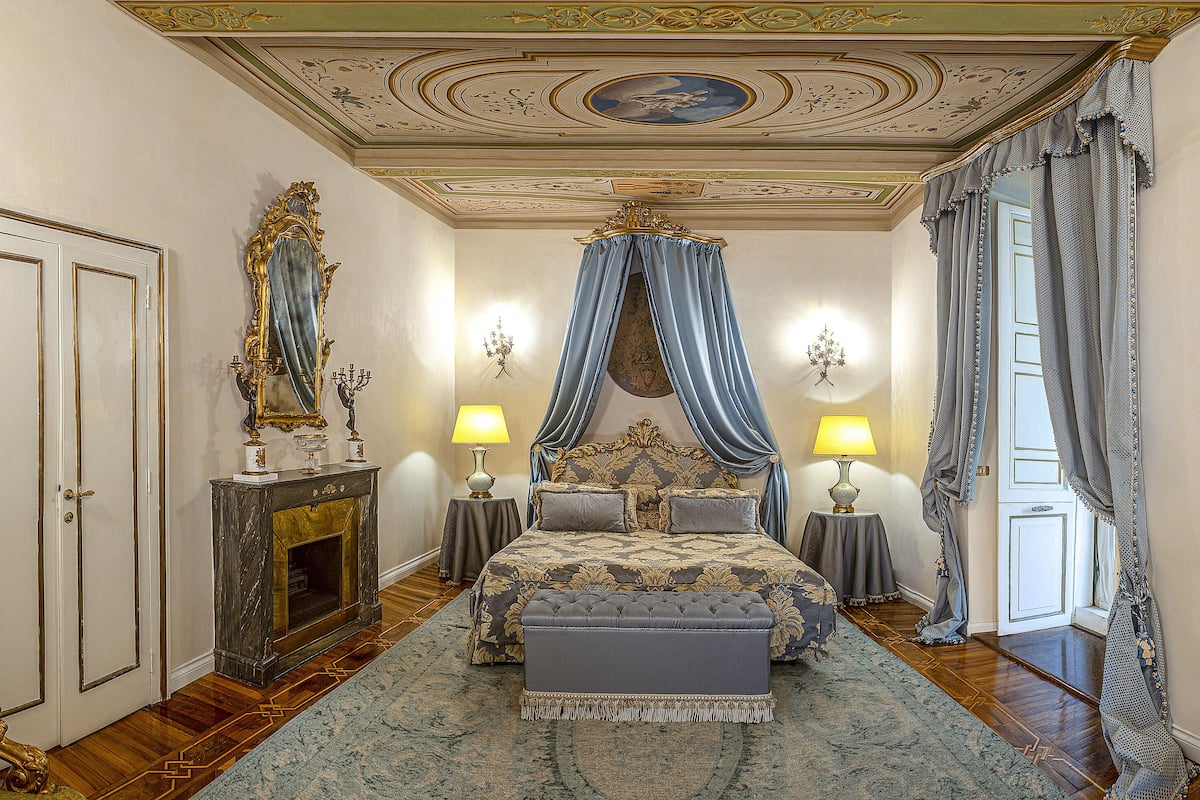A luxurious bedroom with a large bed, ornate ceiling, and classic decor.