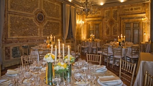 Ein Festsaal mit aufwendigen Wandverzierungen, Kronleuchtern und festlich gedeckten Tischen.
