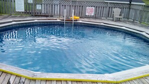 A swimming pool with a wooden deck and a wooden fence in the background. - Mayfield Country Cottages (Mayfield)