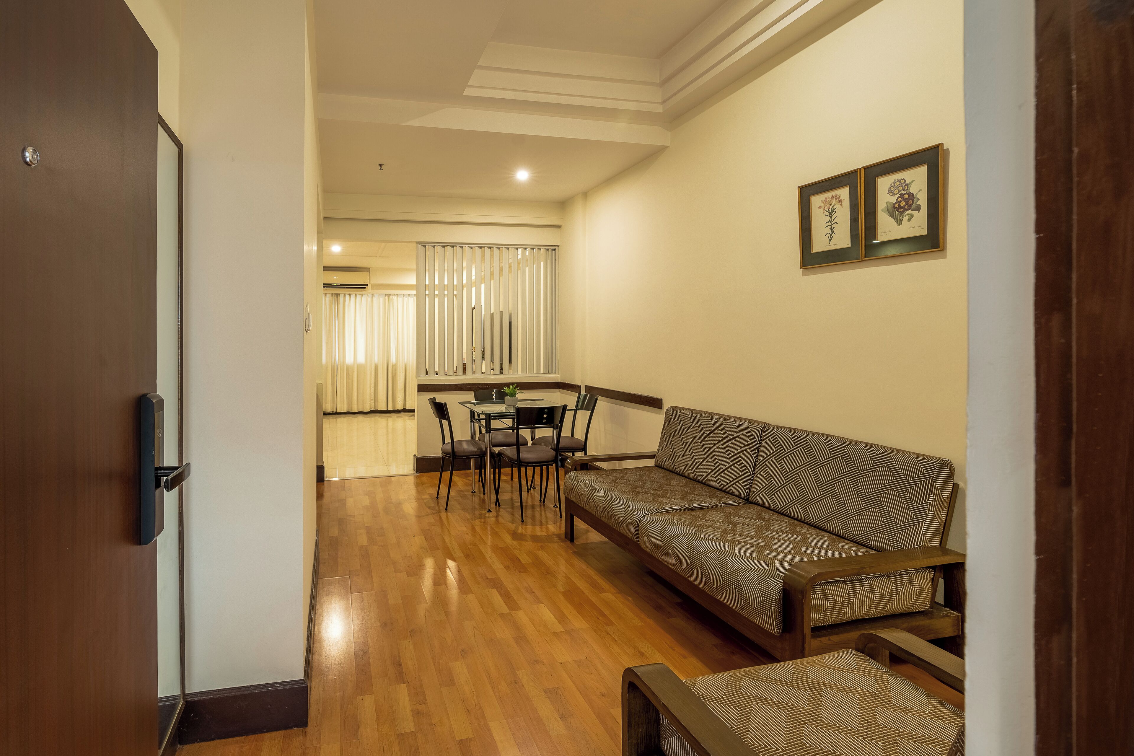 A living area with a sofa, a dining table with chairs, and a wooden floor.