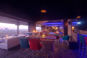 Zona de bar moderna con vistas a la ciudad, taburetes y una iluminación ambiental.
