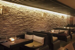 A restaurant with stone walls, cushioned seating, and table settings.