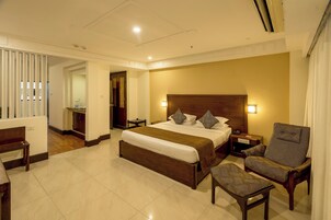Una habitación de hotel con una cama grande, un cabecero de madera, una mesita de noche, una silla y un banco.