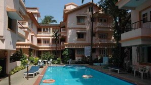 A hotel with a swimming pool, multiple balconies, and outdoor seating areas. - Perola Do Mar (Candolim)