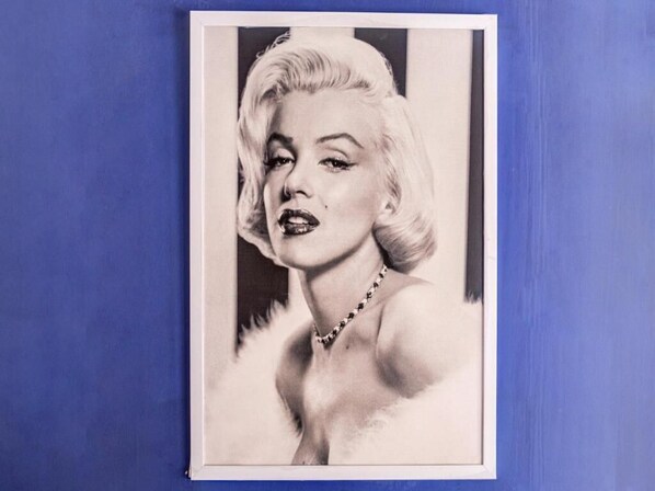 A framed black and white photograph of a person with a necklace, set against a blue background. - Hotel Jayshree (Mumbai)
