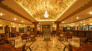 Un vestíbulo amplio con llamativos azulejos, una araña central y una recepción.