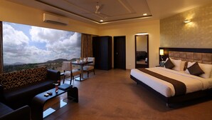 Une chambre d’hôtel avec un grand lit, un canapé, une table à manger et une vue sur l’extérieur.