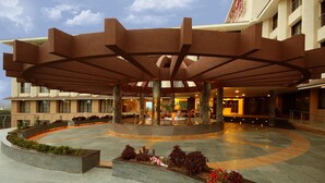 Un hall d’hôtel moderne doté d’un espace salon central, d’une fontaine et d’un espace extérieur abrité.