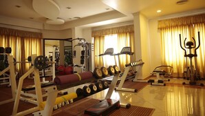 A well-equipped home gym with various exercise machines, weights, and a treadmill. - Joys Palace (Thrissur)