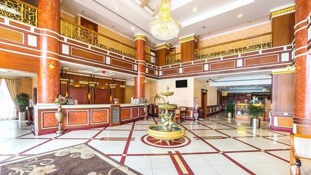 A spacious lobby with a central fountain, multiple reception desks, and a high ceiling with ornate railings. - Joys Palace (Thrissur)
