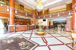 A spacious lobby with a central fountain, multiple reception desks, and a high ceiling with ornate railings. - Joys Palace (Thrissur)