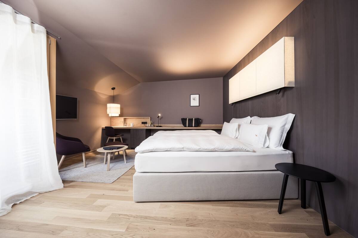 A modern bedroom with a large bed, a desk, and a chair.