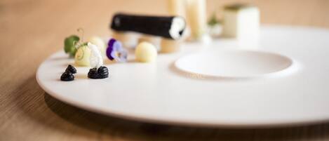 A white plate with various food items and a black object on a wooden surface.