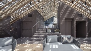 Un interior moderno con techo de madera, una escalera, un sofá y una planta en maceta.