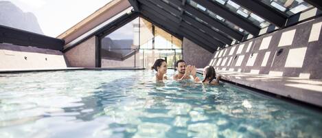 Una piscina con techo de cristal y vista a las montañas.