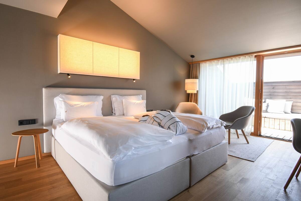 A modern bedroom with a large bed, a small table, and a chair.