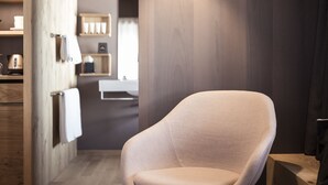 Un interior moderno con suelo de madera, una silla blanca y una lámpara colgante.