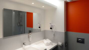 A modern bathroom with a large mirror, two sinks, a shower, and a hairdryer.