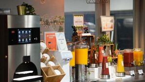 Una estación de bebidas de autoservicio con varios dispensadores, una máquina de café y un refrigerador.