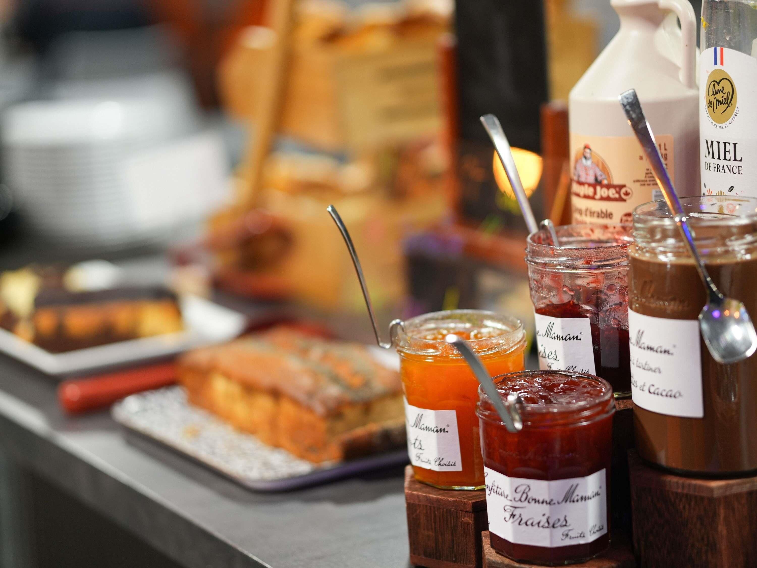 A variety of food items including jars of jam and honey, a bottle of Miel de France honey, and a tray of baked goods.