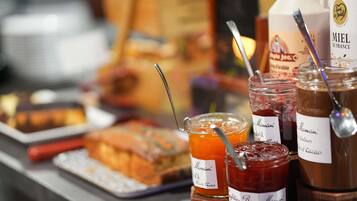 A variety of food items including jars of jam and honey, a bottle of Miel de France honey, and a tray of baked goods.