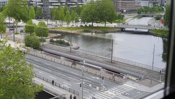 A riverside view with a pedestrian bridge, a modern building, and a distant cityscape.
