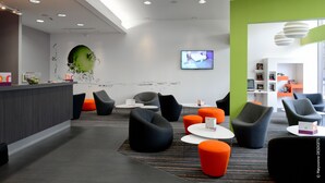 Un área de recepción moderna con mostrador, asientos y una pantalla de televisión.