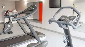 A gym with treadmills, a stationary bike, and a wall-mounted TV.