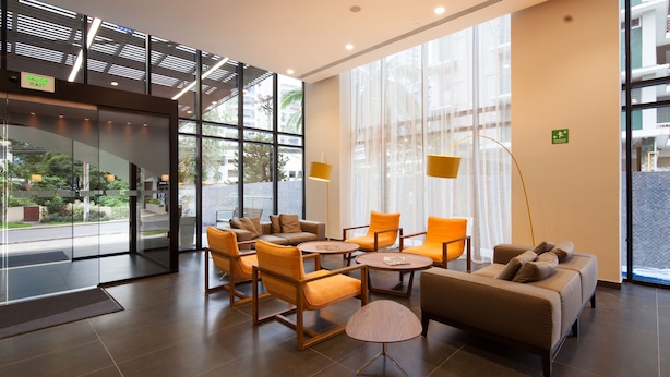 Eine moderne Lobby mit Sitzbereichen, großen Fenstern und einem gut sichtbaren Ausgangsschild.