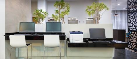 A modern office space with two desks, two chairs, and two printers.