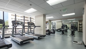 Ein Fitnessstudio mit Laufbändern, Crosstrainern und weiteren Trainingsgeräten.