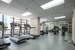 Uma academia com esteiras, elípticos e outros equipamentos de ginástica.