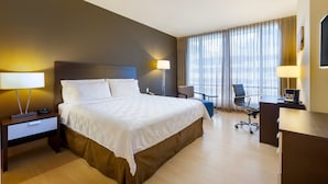 Ein Hotelzimmer mit einem großen Bett, einem Schreibtisch, einem Stuhl und einer Schreibtischlampe.