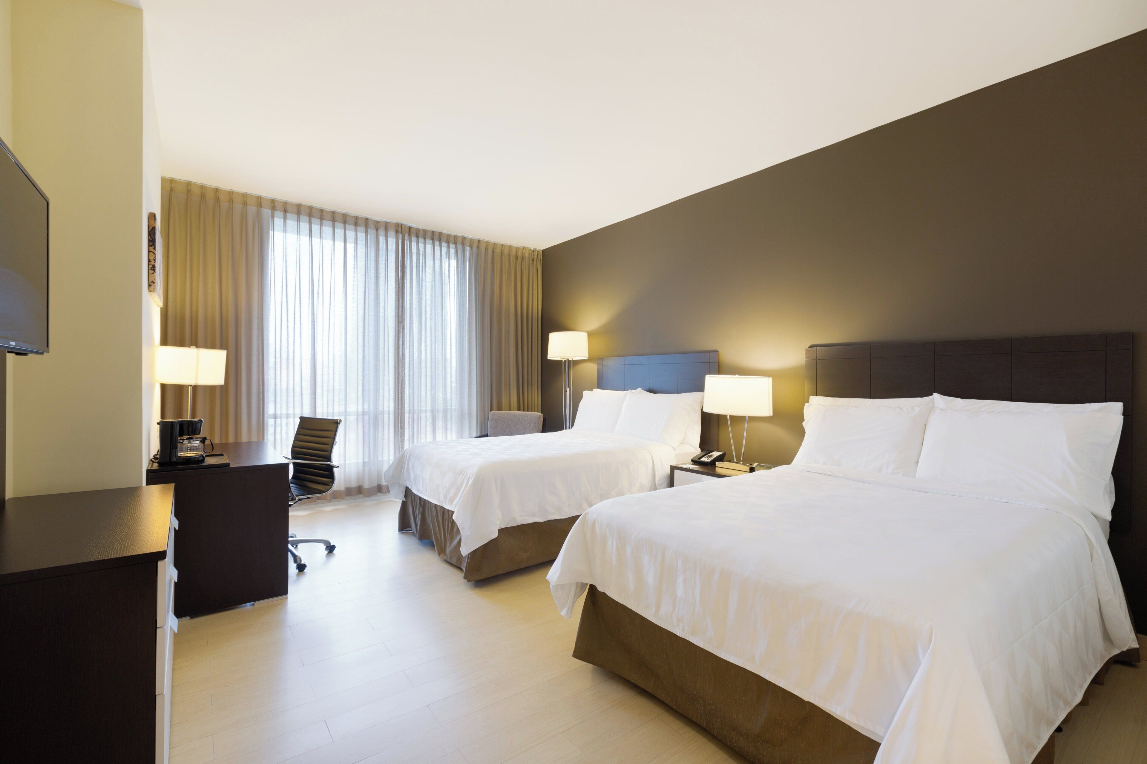 Een hotelkamer met twee bedden, een bureau, een stoel en een televisie.