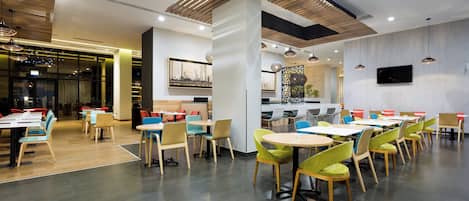 A modern restaurant interior with high ceilings, wooden slats, and a variety of seating options.