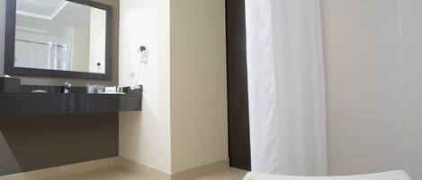 A bathroom with a large mirror, a sink, and a shower area.