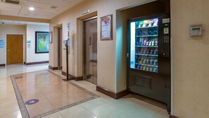 A hotel corridor with a vending machine, elevators, and a sign for breakfast. - Holiday Inn Express Hotel & Suites Cuernavaca by IHG (Cuernavaca)