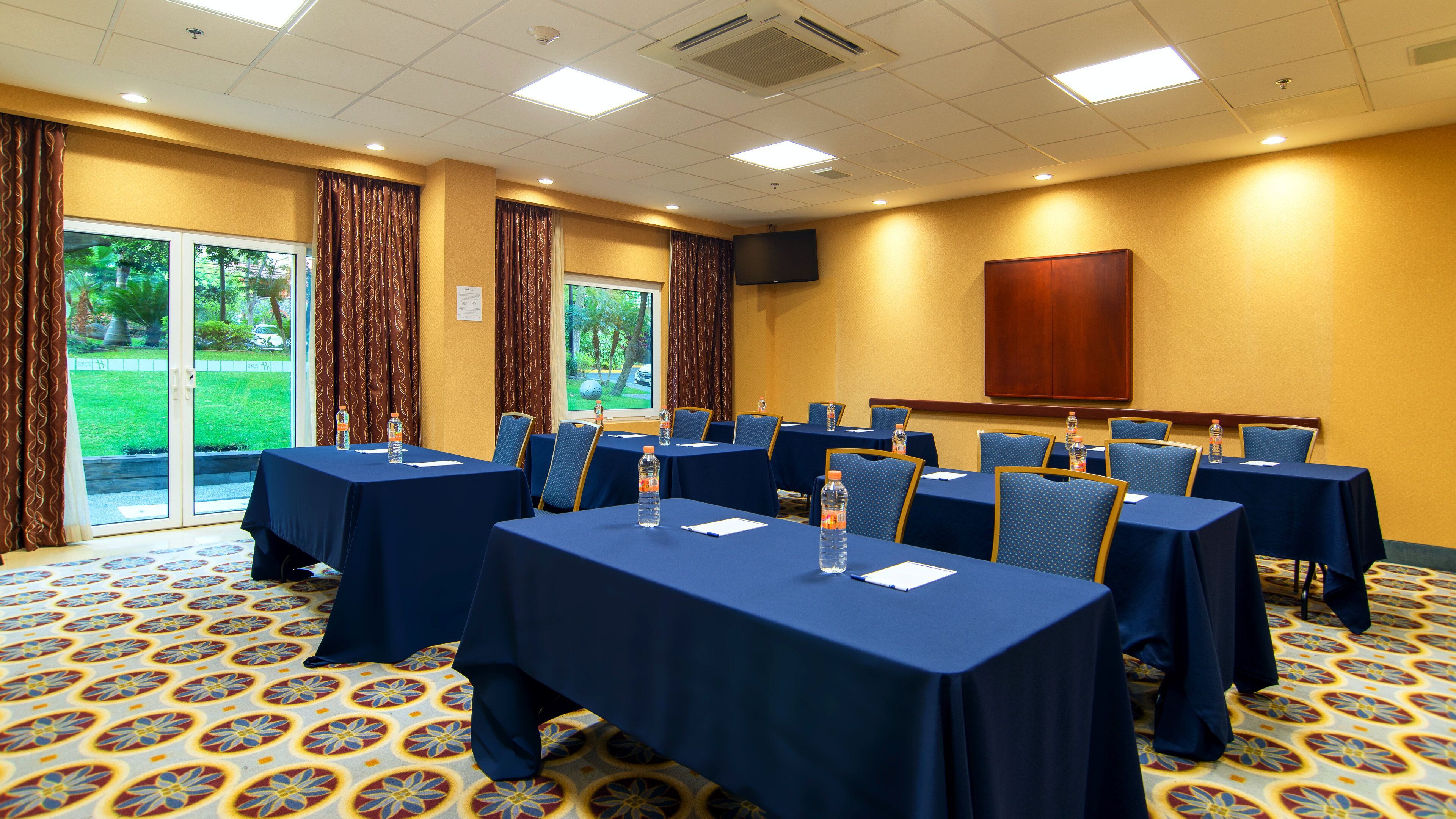 A conference room with tables set for meetings, equipped with water bottles and notepads.