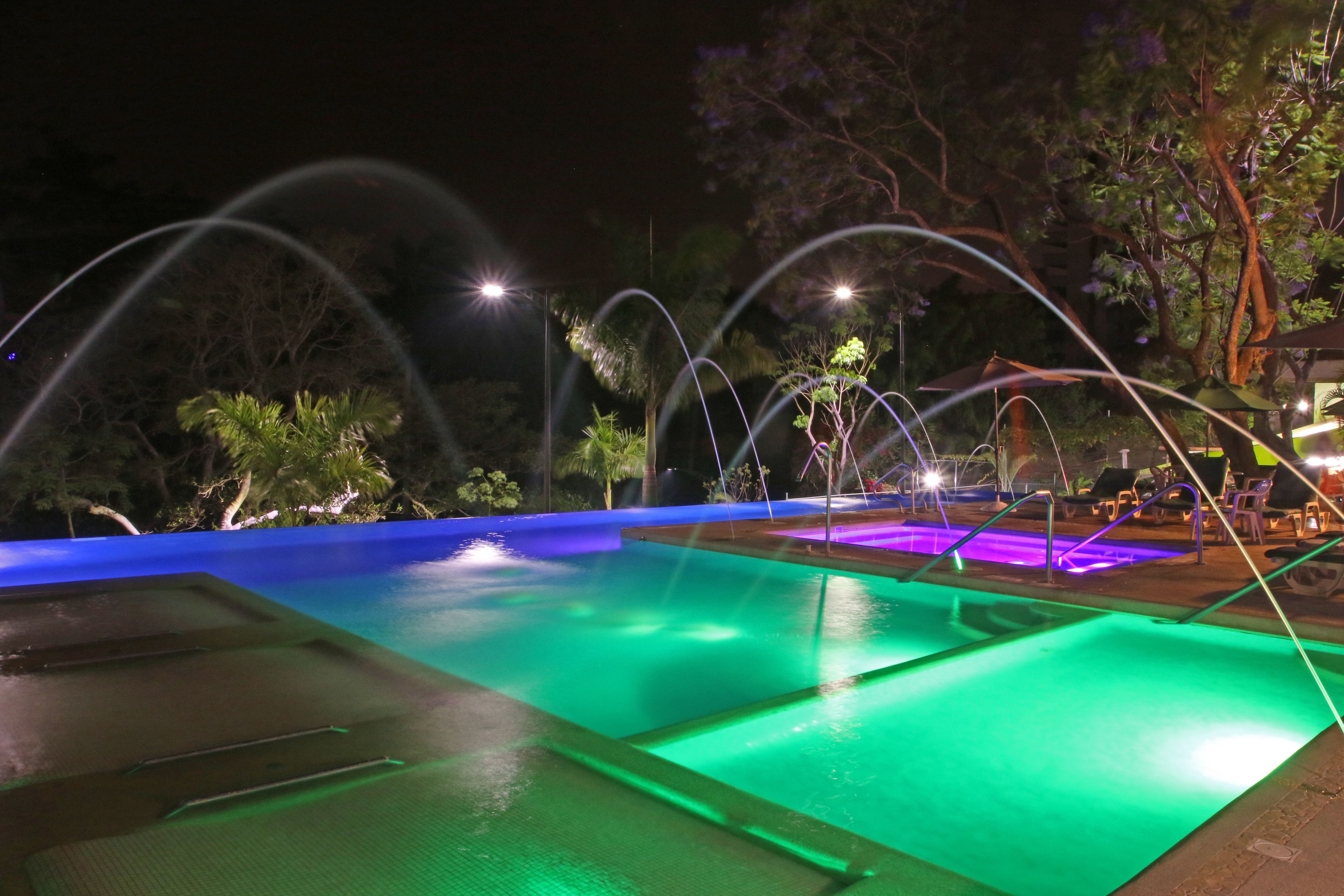 Una piscina con múltiples carriles, rodeada de árboles y zonas de estar al aire libre.