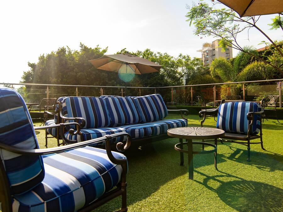 A patio with striped blue and white outdoor furniture, including a sofa and chairs, and a small round table.