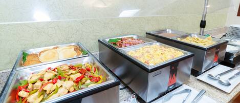 A buffet with various food options including pancakes, scrambled eggs, and a stir-fry dish.