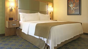 Quarto de hotel com cama, mesas de cabeceira, luminária na parede e um quadro.